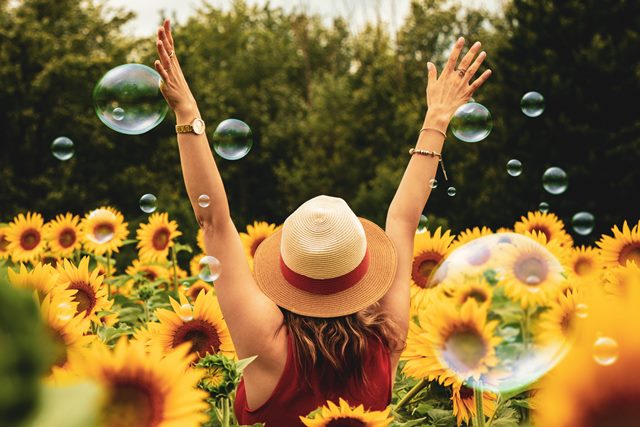 Happy person in fied ith sunflowers and bubbles