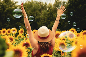 Happy person in fied ith sunflowers and bubbles
