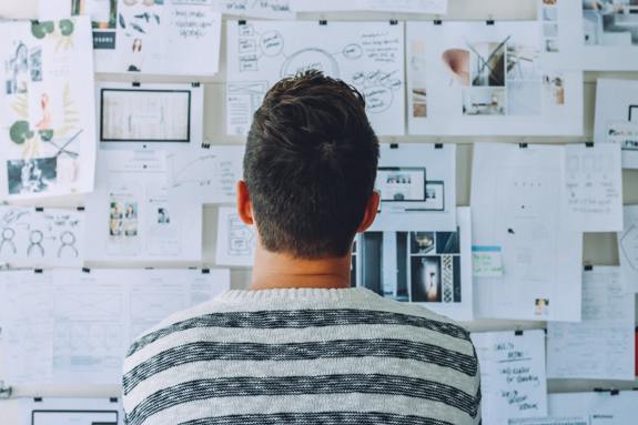 Man studying papers on a bulletin board.